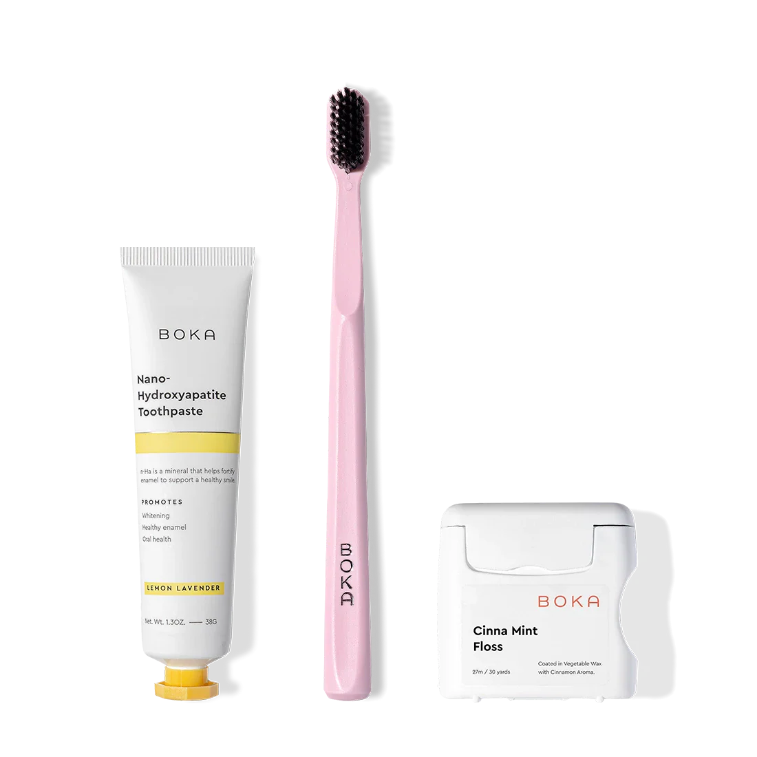 Travel Kit: toothpaste tube, pink charcoal-bristle toothbrush & teflon-free floss on white background.