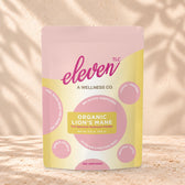 Eleven TLC Organic Lion's Mane Mushroom Powder 500g stand-up pouch on travertine stone against a warm cream plaster wall, lit from the left with a soft shadow to the right.