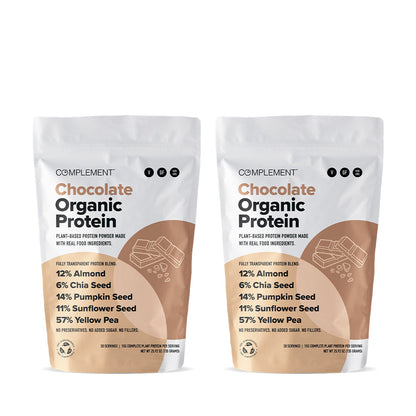Two bags of Complement brand Chocolate Organic Protein powder are displayed. Each bag highlights ingredients like almond, chia seed, pumpkin seed, sunflower seed, and yellow pea. The bags are white with brown accents and a small chocolate icon.
