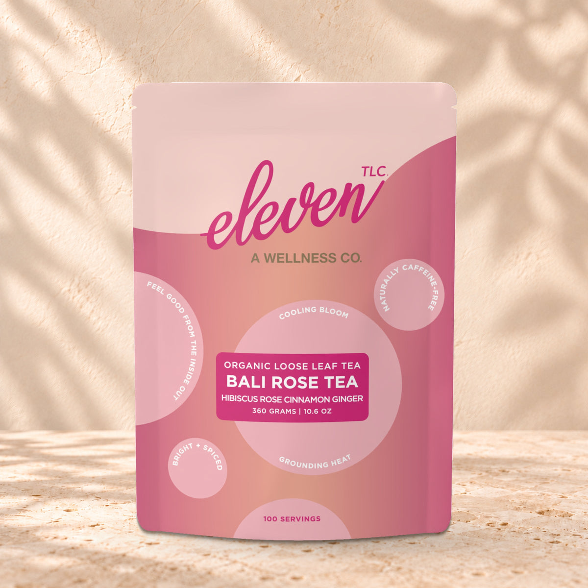 Eleven TLC Bali Rose Loose Leaf Tea 360g stand-up pouch on travertine stone against a warm cream plaster wall, lit from the left with a soft shadow to the right.
