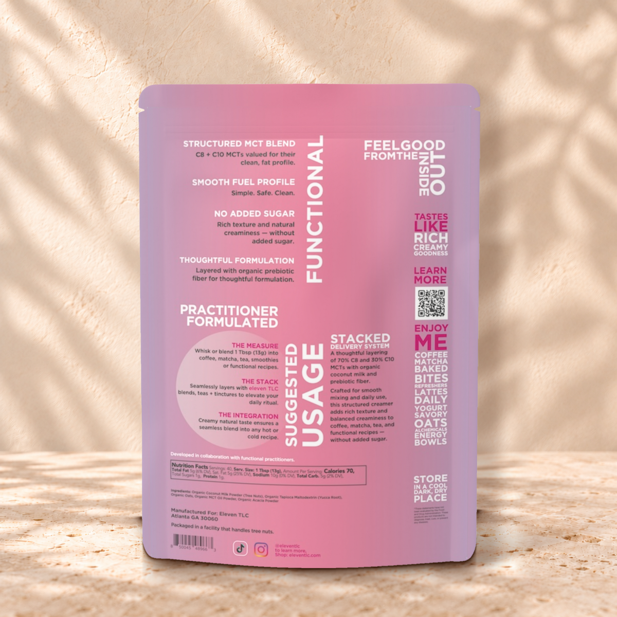 Back panel of the Eleven TLC Organic Coconut MCT Oat Creamer 500g pouch on travertine against a warm cream plaster wall, with suggested usage, nutrition facts, ingredients and a QR code.