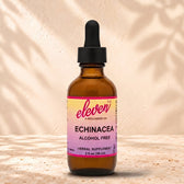 Eleven TLC Echinacea alcohol-free herbal supplement tincture, 2 fl oz (59 ml) amber glass dropper bottle with pink and yellow label, on a travertine ledge against a cream wall with leaf shadows