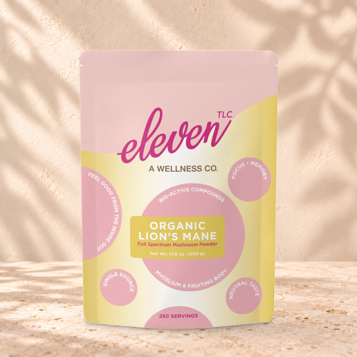 Eleven TLC Organic Lion's Mane Mushroom Powder 500g stand-up pouch on travertine stone against a warm cream plaster wall, lit from the left with a soft shadow to the right.