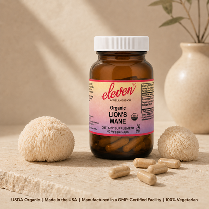 Eleven TLC 60-count Organic Lion's Mane mushroom capsules bottle displayed on neutral surface with dried mushroom specimens.