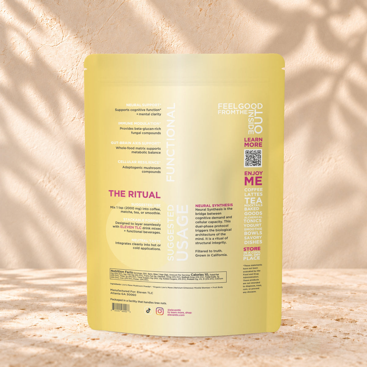 Back view of an Eleven TLC Lion’s Mane Mushroom Powder 500g pouch on warm travertine against a cream plaster wall with botanical shadows.
