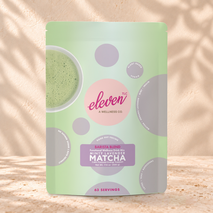 Eleven TLC Minty Lavender Matcha 500g pouch standing on a travertine ledge against warm plaster, with a contact shadow beneath its base and a soft shadow to the right.