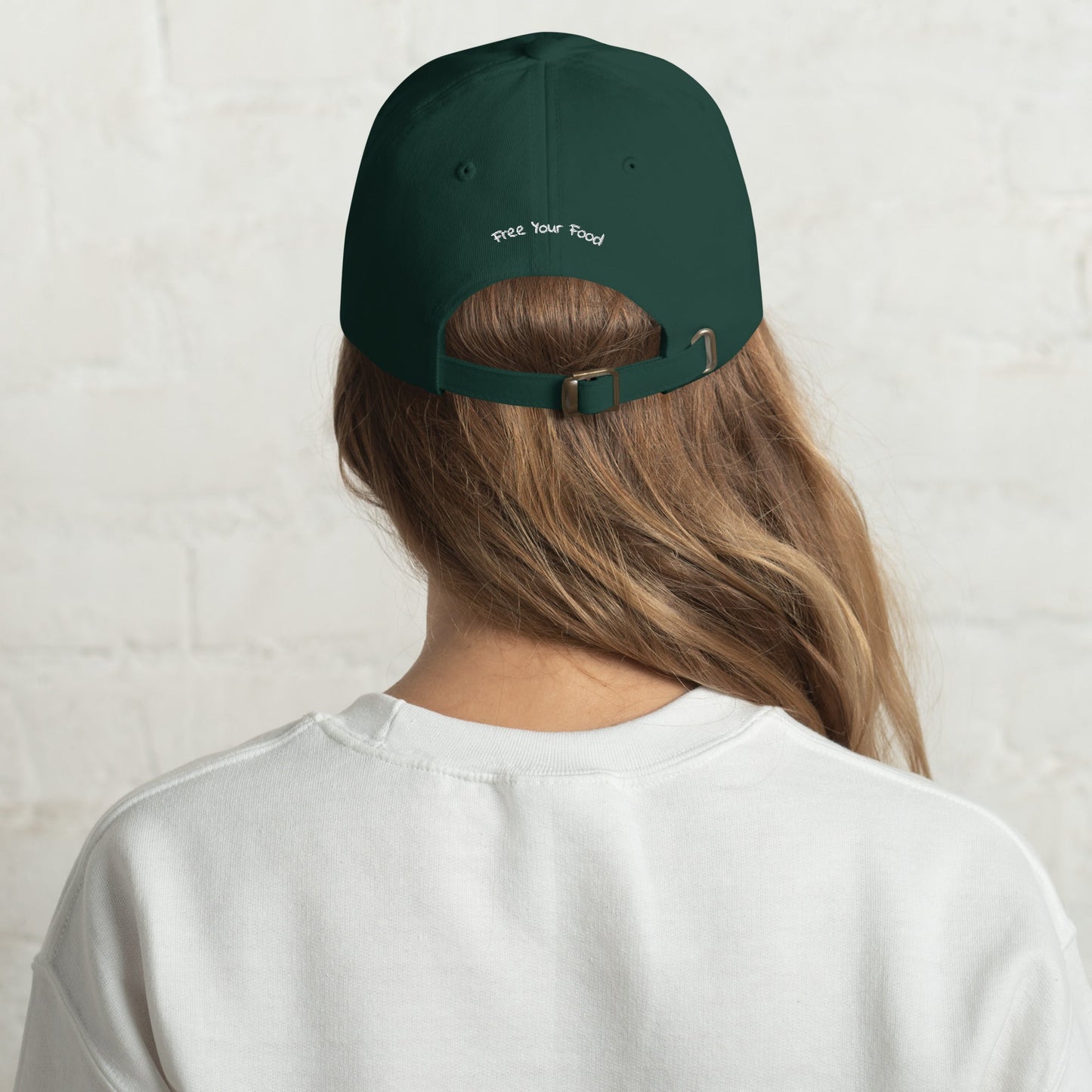 Back view of the Everyday Bare Life Cap in spruce green worn by a model, showing 'Free Your Food' embroidered above the adjustable strap.
