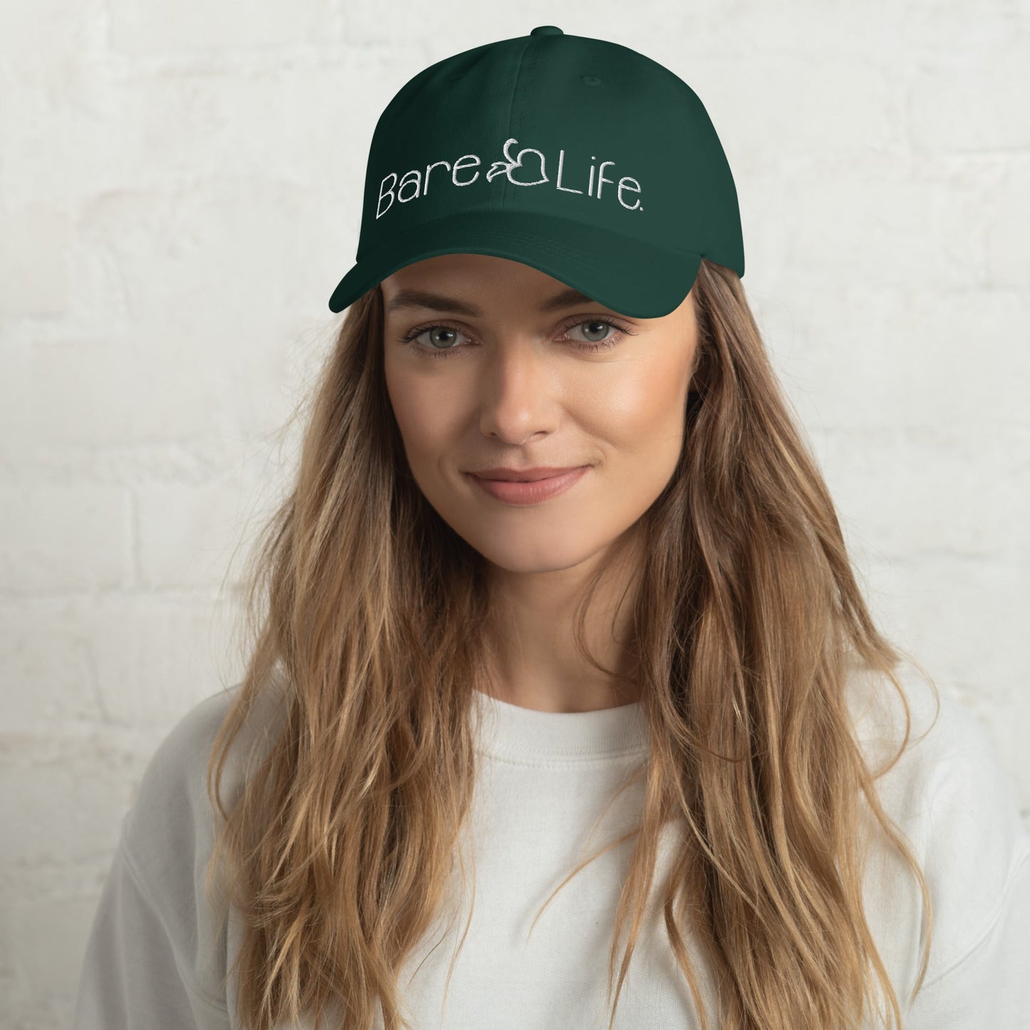 Model wearing the Everyday Bare Life Cap in spruce green, showcasing the embroidered Bare Life logo on the front.