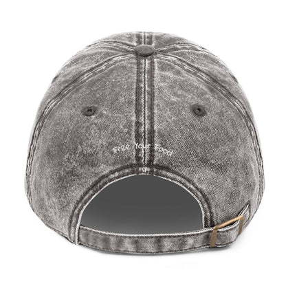 Back view of Bare Life's charcoal gray denim Cocoa-Chic Cap with 'Free Your Food' embroidered above the opening and antique brass buckle strap.