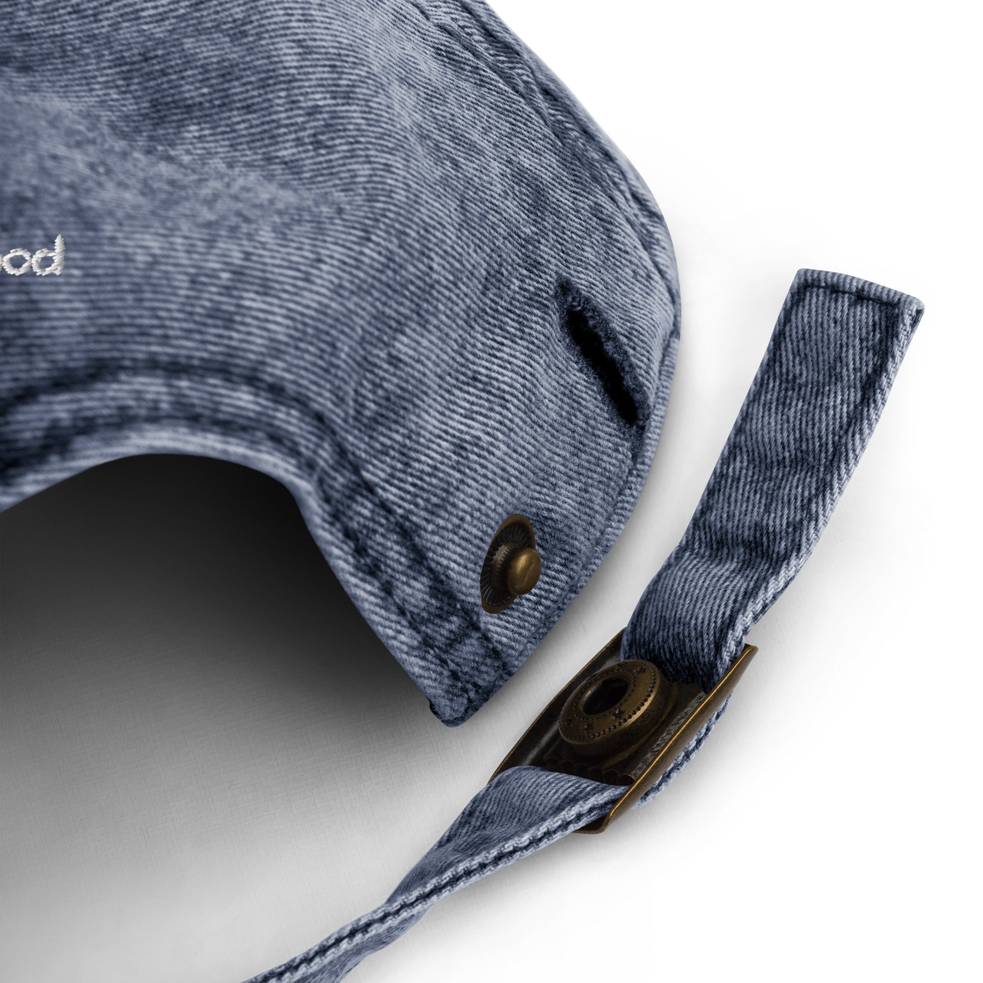 Close-up detail of the strap and buckle on Bare Life's navy Cocoa-Chic Cap, showing the textured denim and antique brass hardware.