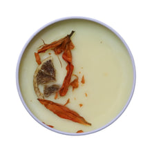 Unsolicited Sunshine Wickless Candle shows orange colored botanicals on top of the wax